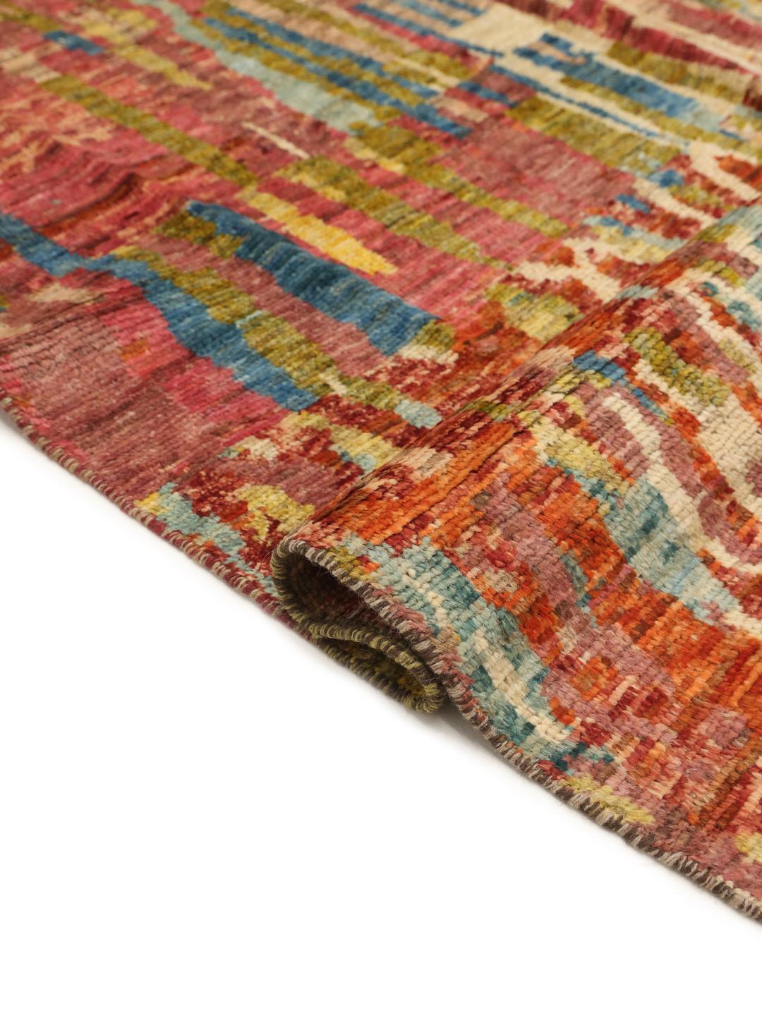 A large, hand-knotted Afghan rug featuring a vibrant, multicolored abstract pattern.