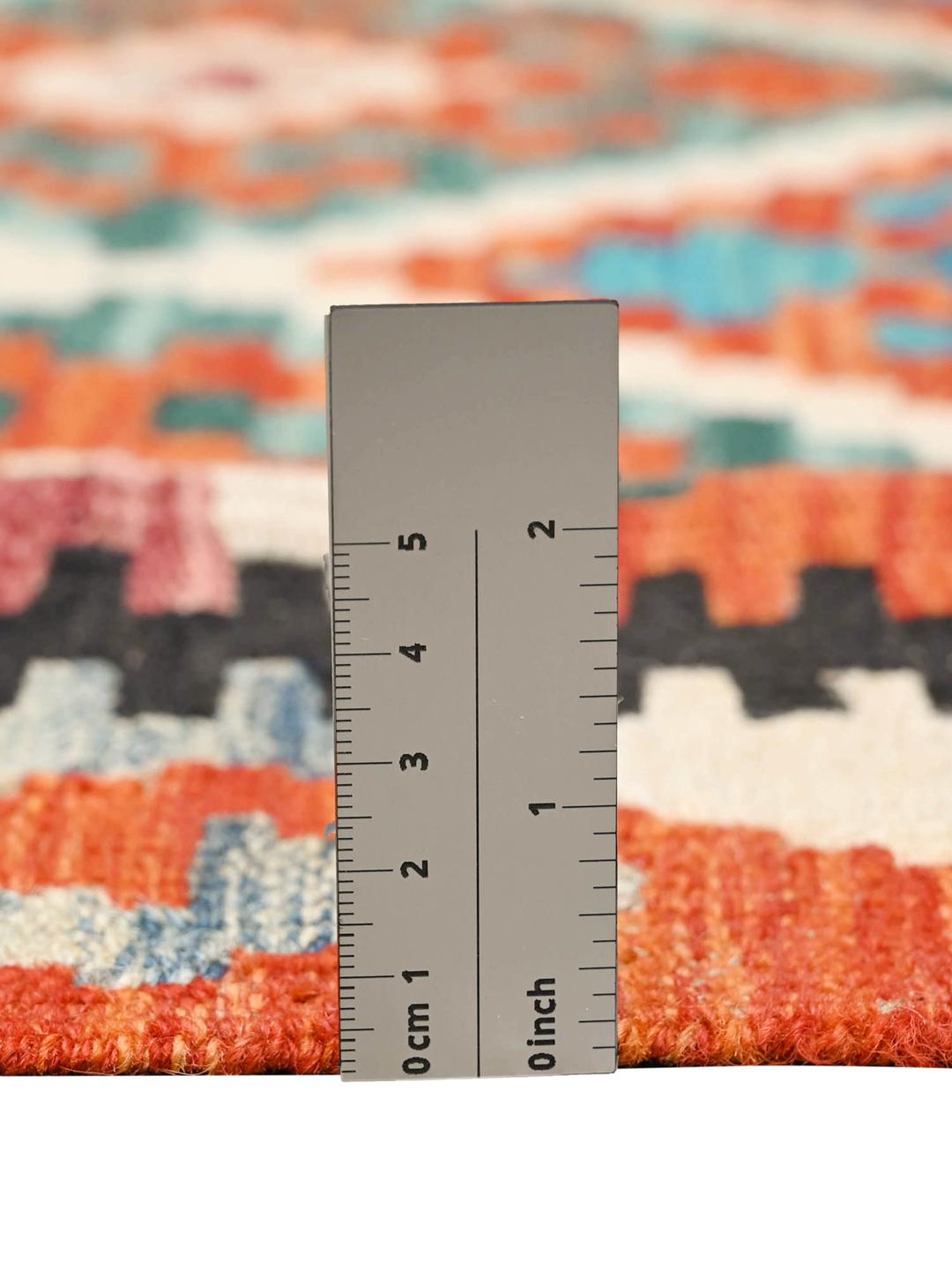 A hand-woven, one-of-a-kind Kelim rug from Afghanistan featuring a multicoloured geometric diamond pattern.