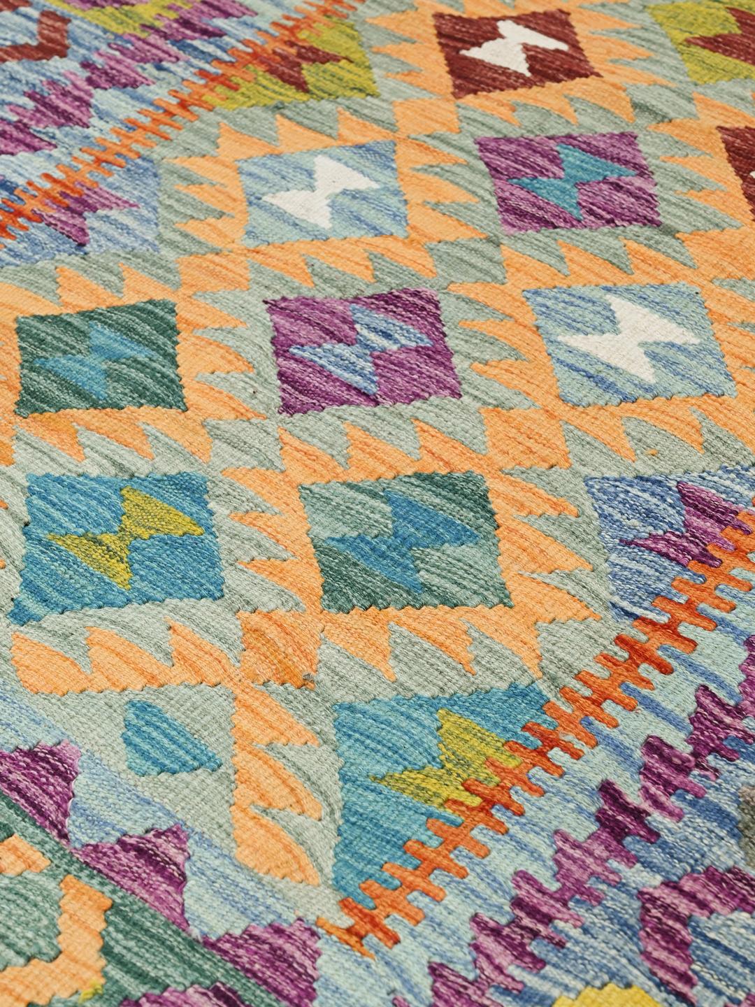 A hand-woven Afghan Kelim rug featuring a vibrant multicolour geometric pattern on a light background.