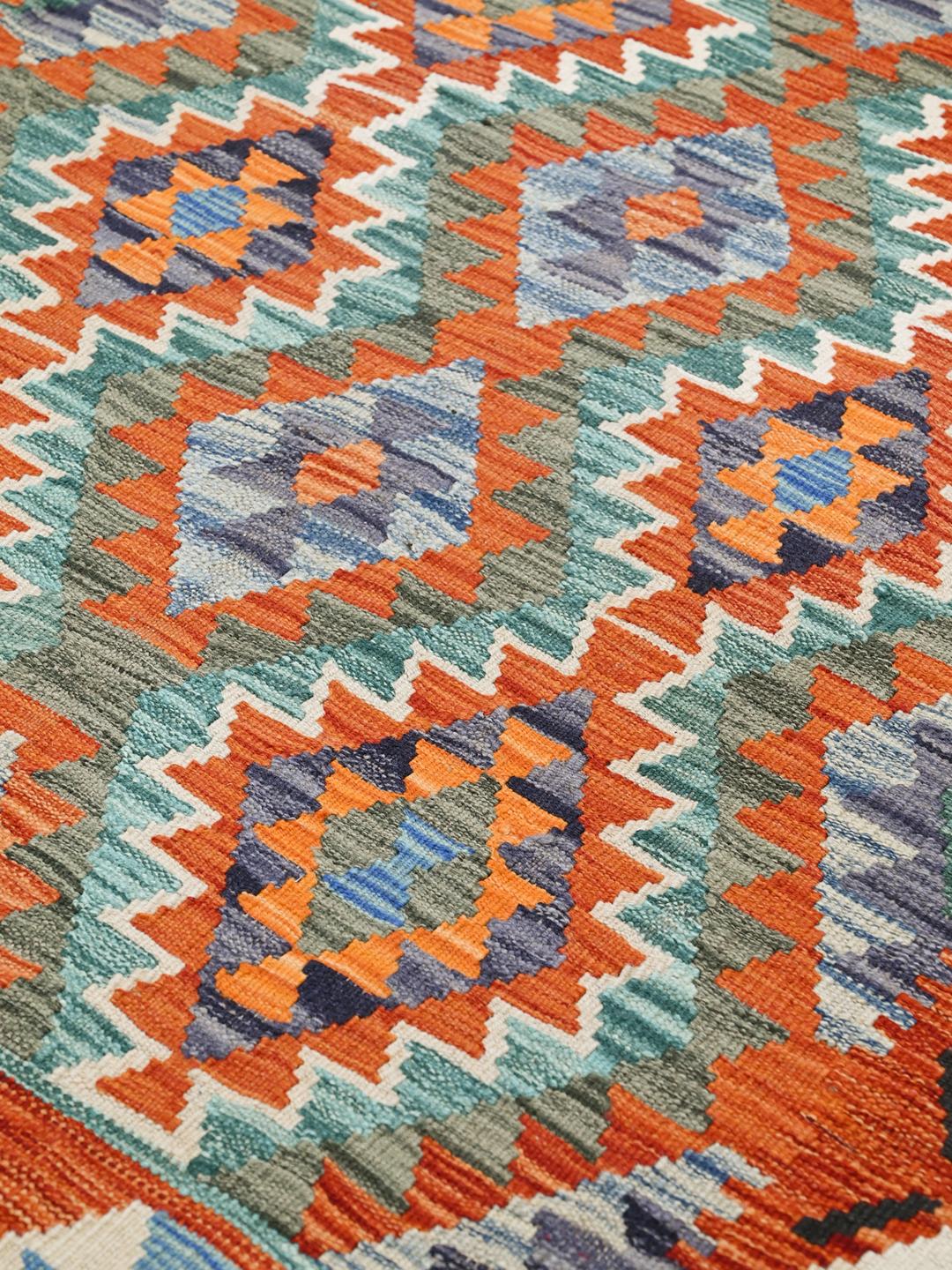 Hand-woven Afghan Kelim rug with geometric diamond patterns in orange and blue