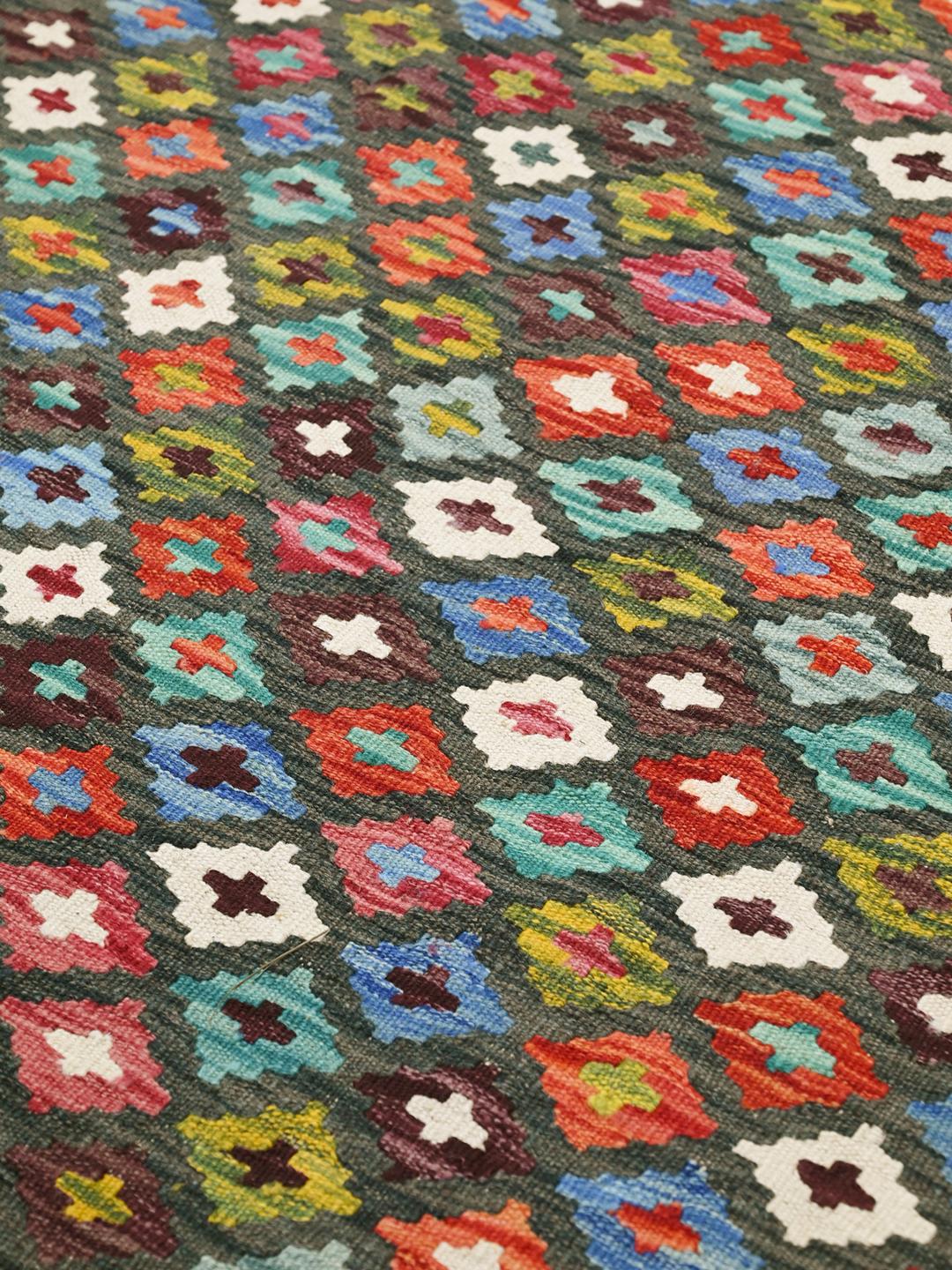 Ręcznie tkany afgański dywan typu kilim z geometrycznym, wielokolorowym wzorem na ciemnym tle