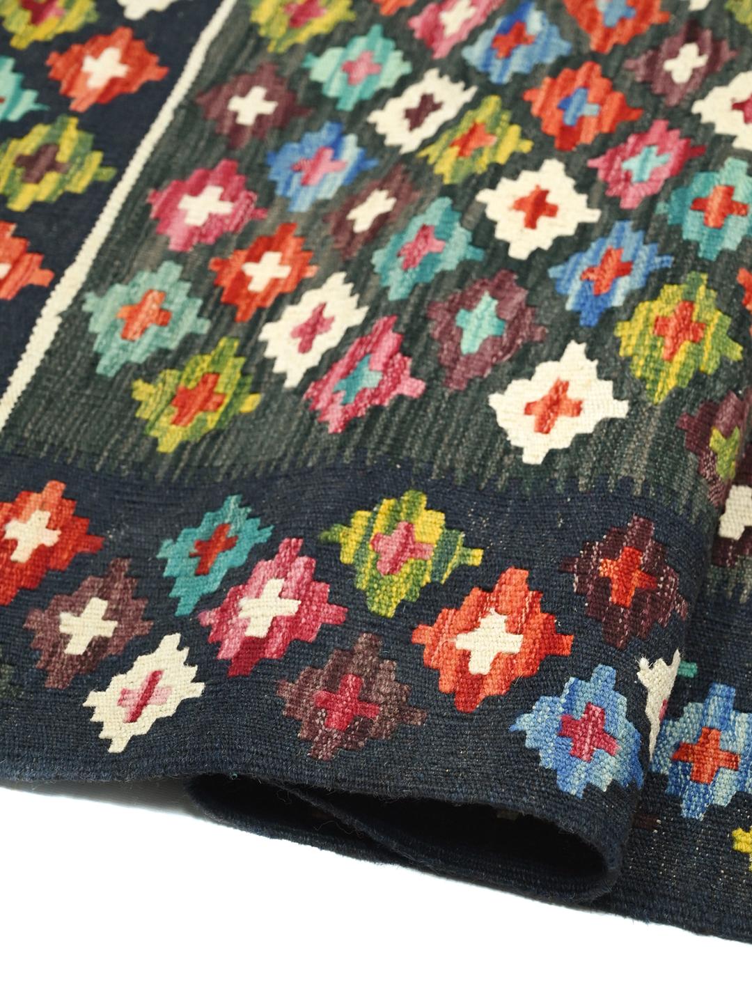 Ręcznie tkany afgański dywan typu kilim z geometrycznym, wielokolorowym wzorem na ciemnym tle