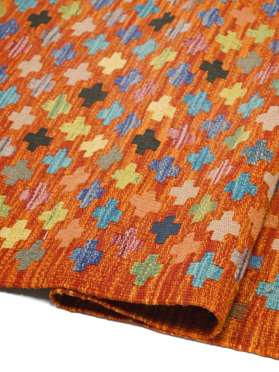 A hand-woven Afghan Kelim rug featuring a vibrant orange field with multi-coloured geometric crosses.