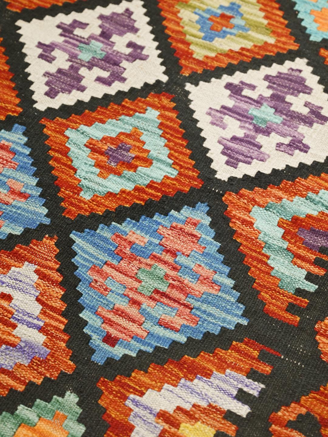 A vibrant Afghan Kelim runner with a geometric diamond pattern in multicolor wool.