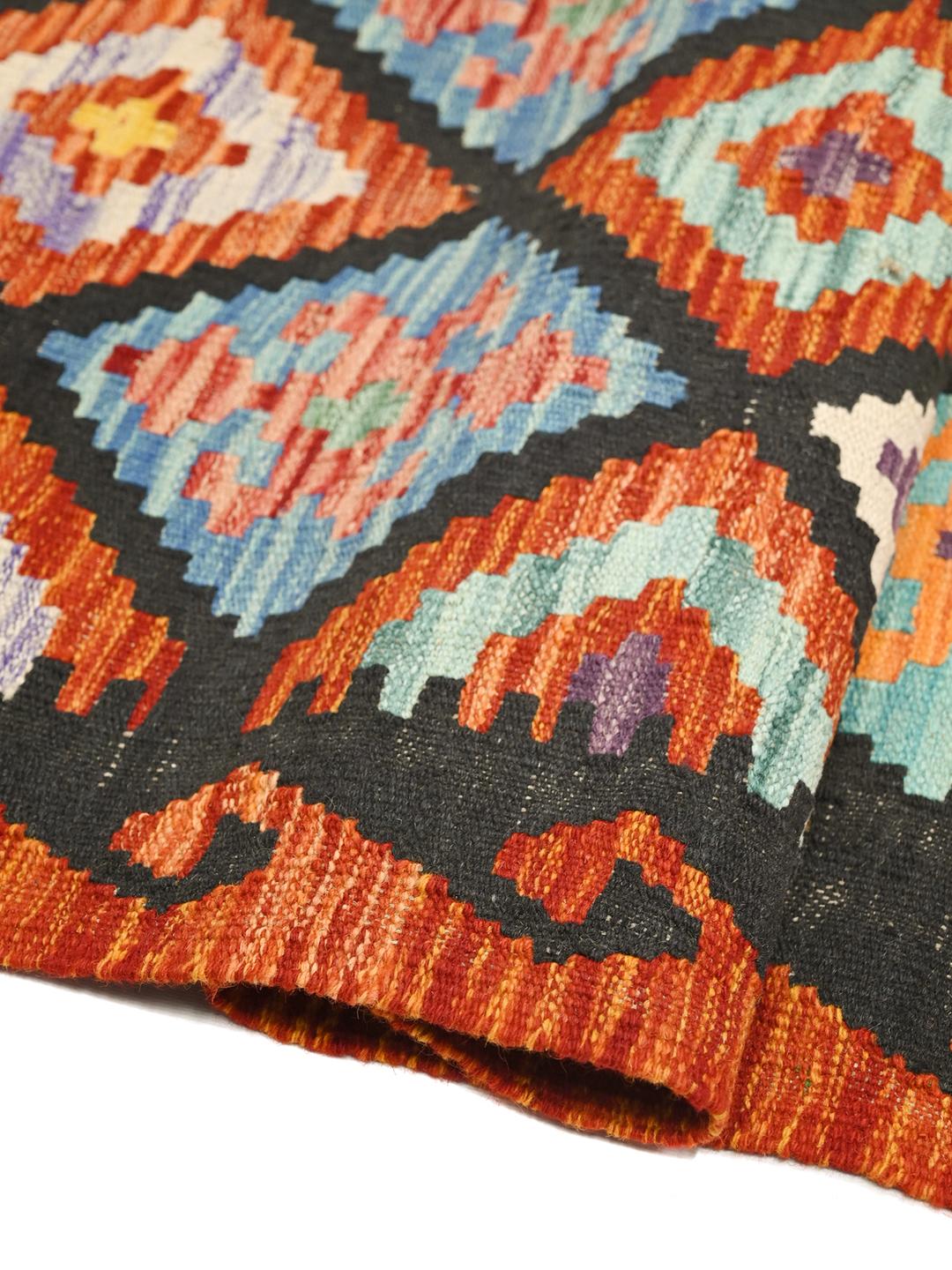 A vibrant Afghan Kelim runner with a geometric diamond pattern in multicolor wool.