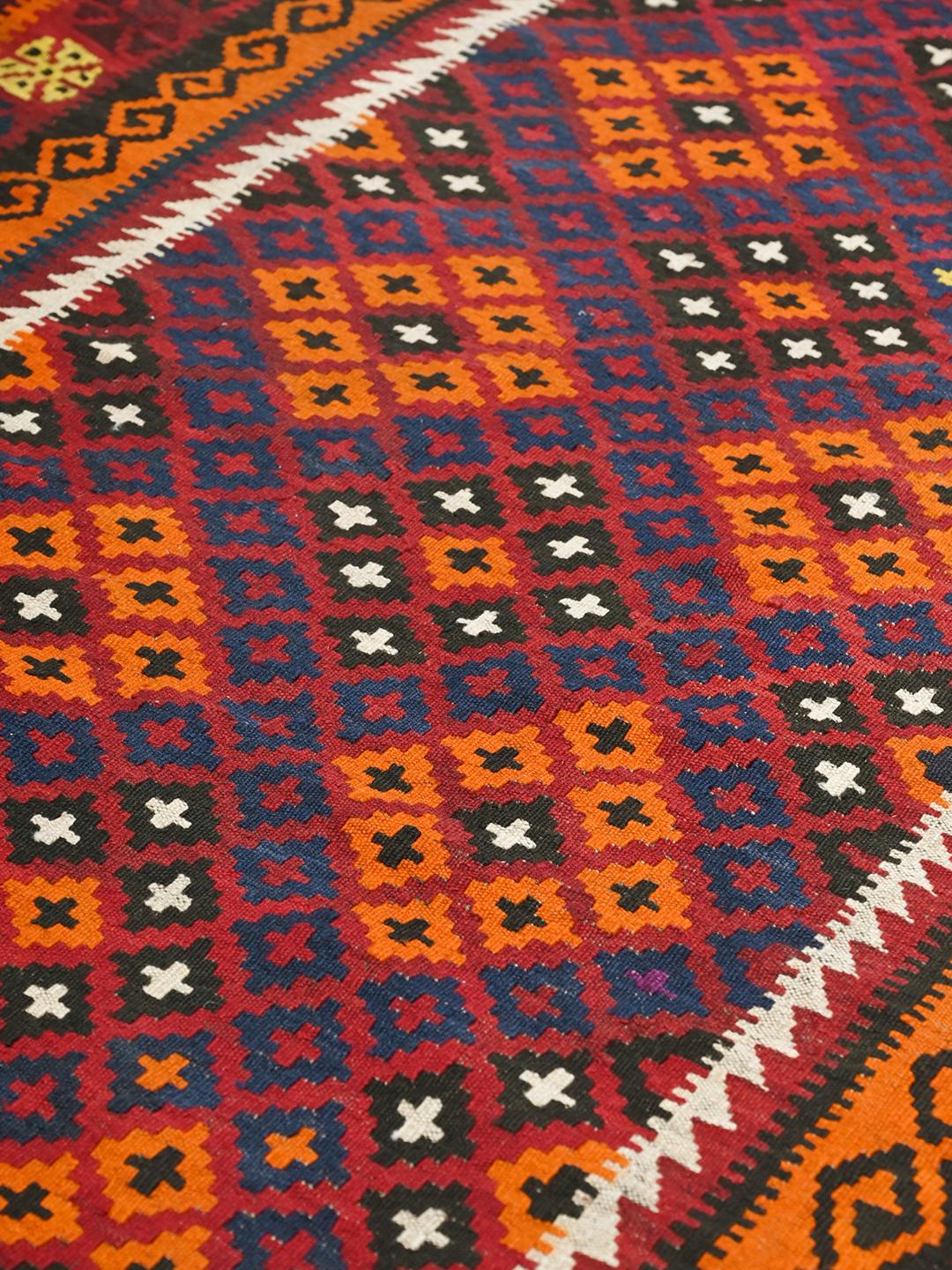 Een groot, handgeweven Kelim Maimane vloerkleed uit Afghanistan in tinten rood en blauw met geometrische patronen.
