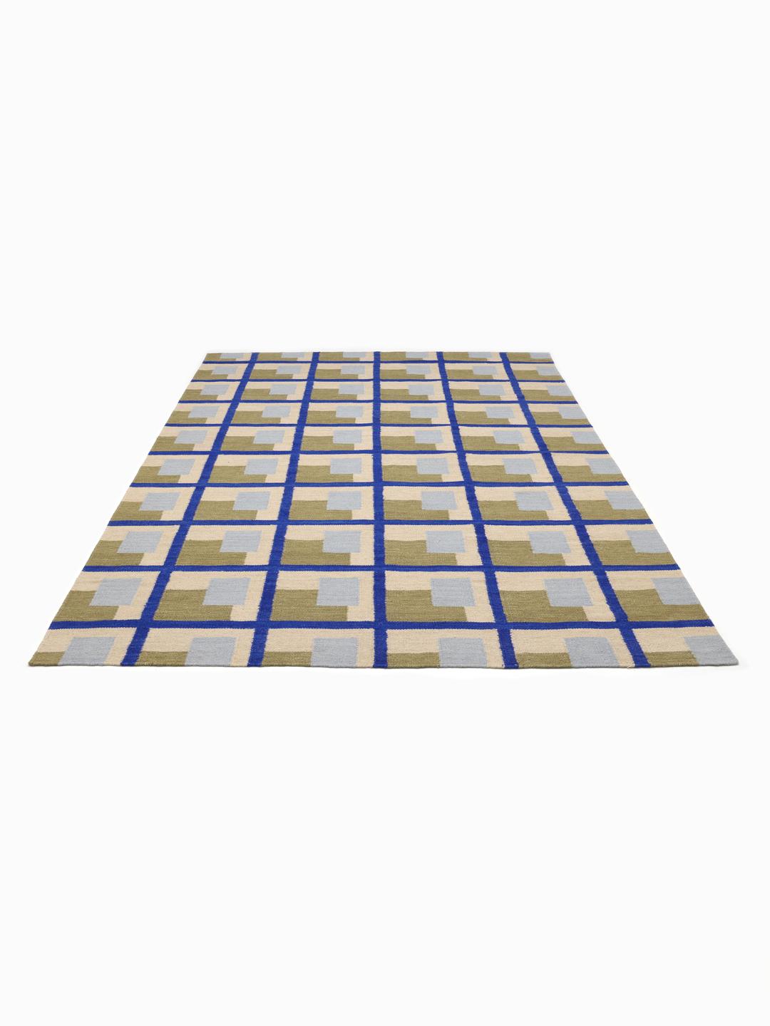 Een handgeweven groen vloerkleed met een geometrisch rasterpatroon