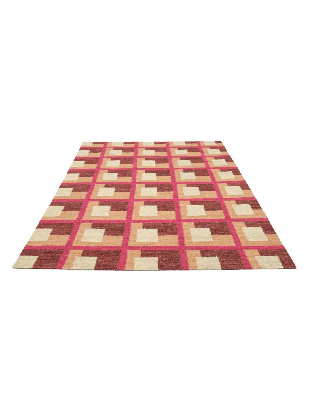 Roze en meerkleurig tapijt met een geometrisch patroon op een houten vloer.
