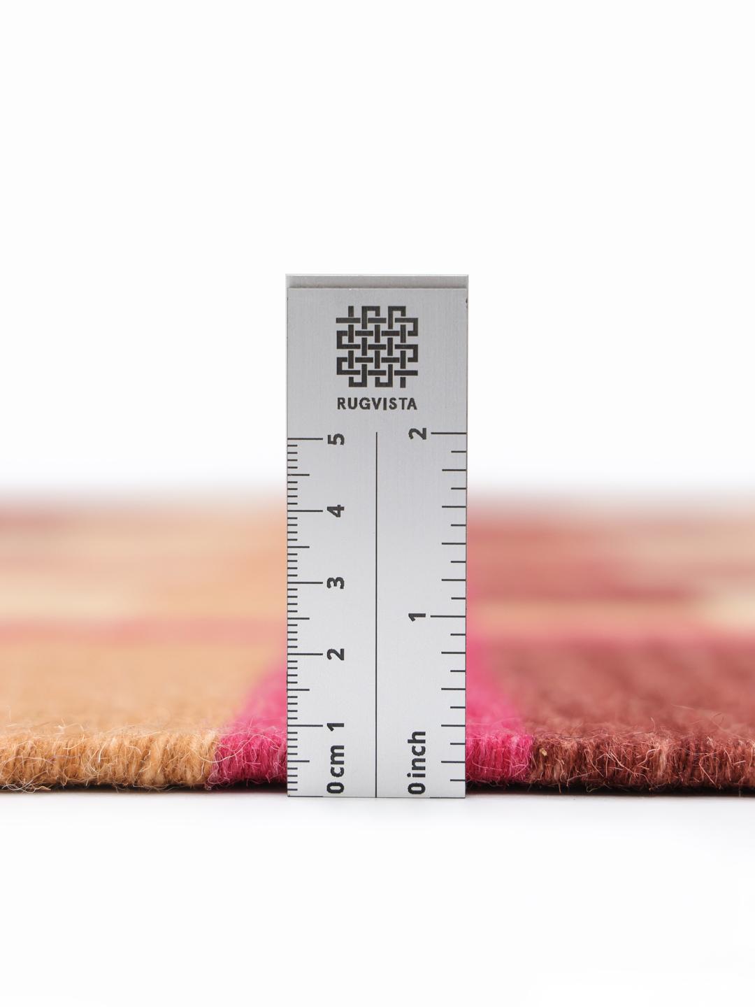 Roze en meerkleurig tapijt met een geometrisch patroon op een houten vloer.