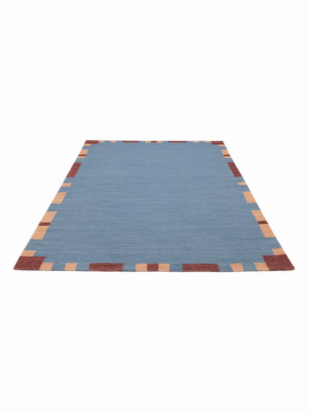 blauw en meerkleurig wollen tapijt met een geometrische rand