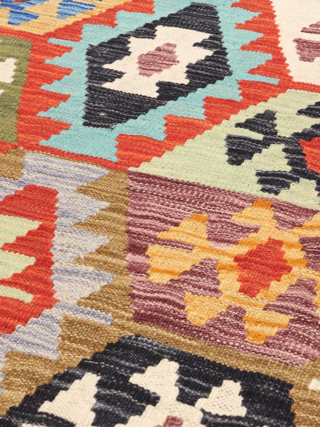 A long, rectangular Afghan runner featuring a vibrant, multi-coloured geometric pattern.