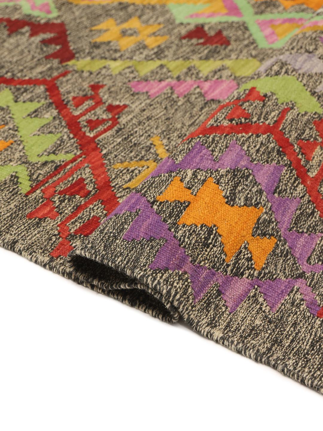 Hand-woven Afghan Kelim rug featuring a dark background with vibrant geometric patterns