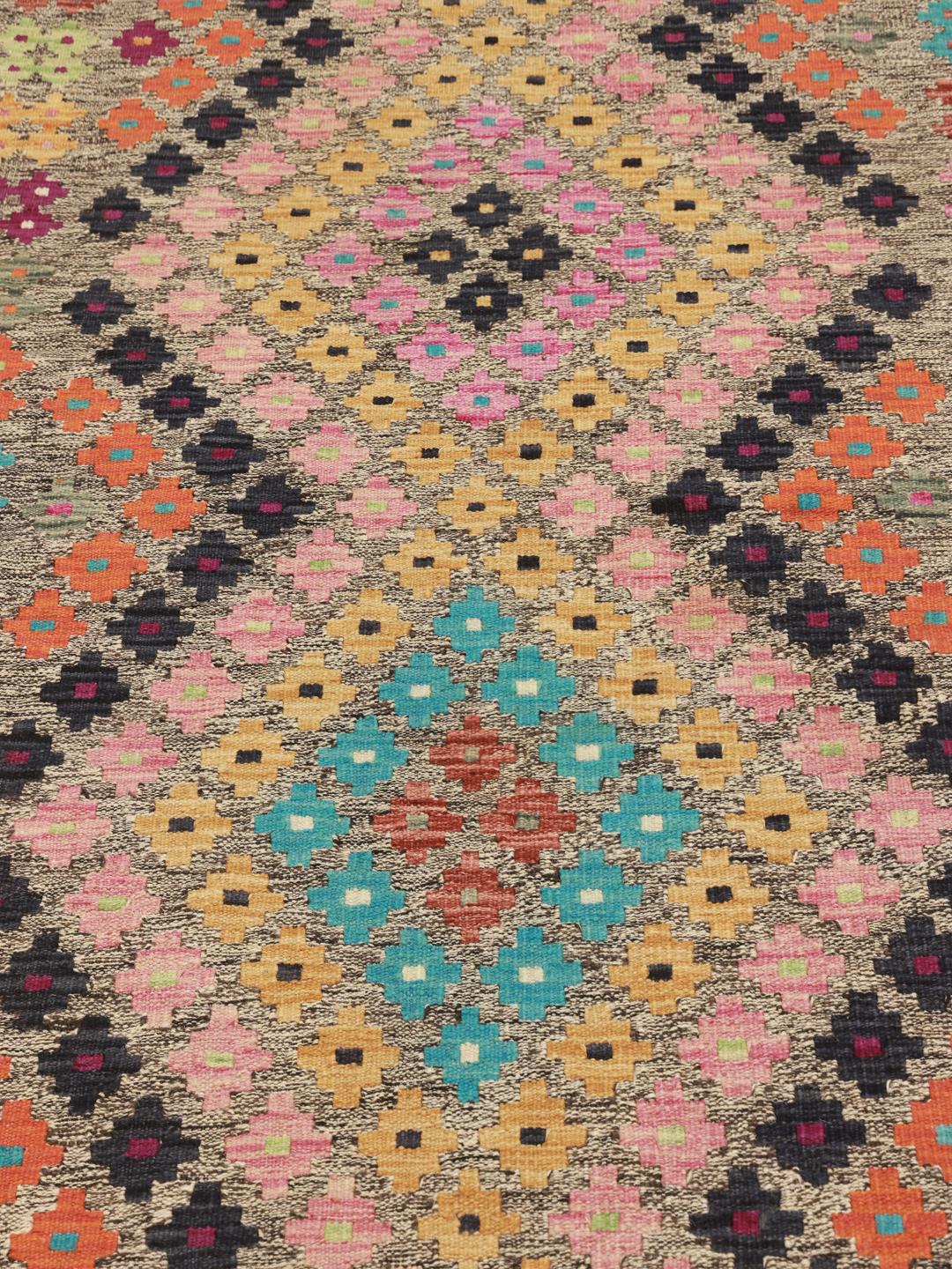 Hand-woven Afghan runner with colourful geometric patterns on a grey background