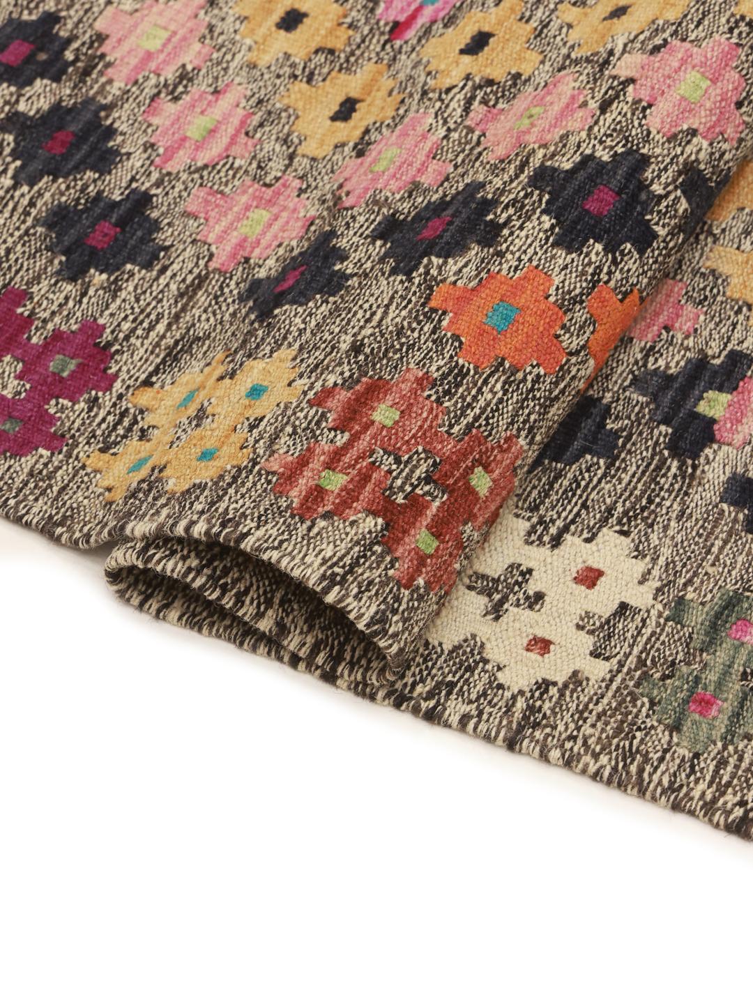 Hand-woven Afghan runner with colourful geometric patterns on a grey background