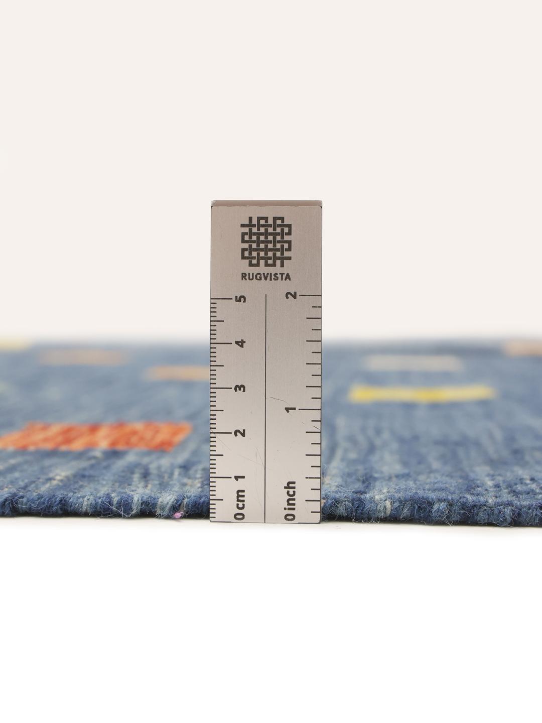 Een handgeweven Kilim-tapijt uit Afghanistan met een blauwe achtergrond en veelkleurige vierkante patronen.