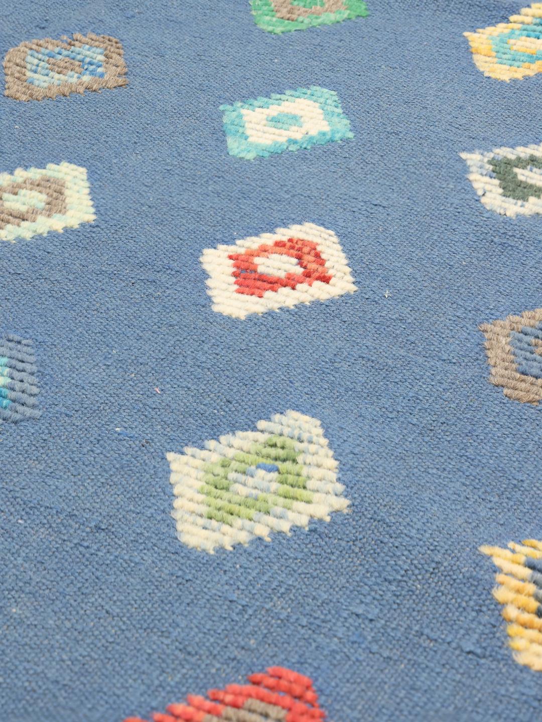 Hand-woven Afghan Kilim rug with multicoloured diamond patterns on a blue field
