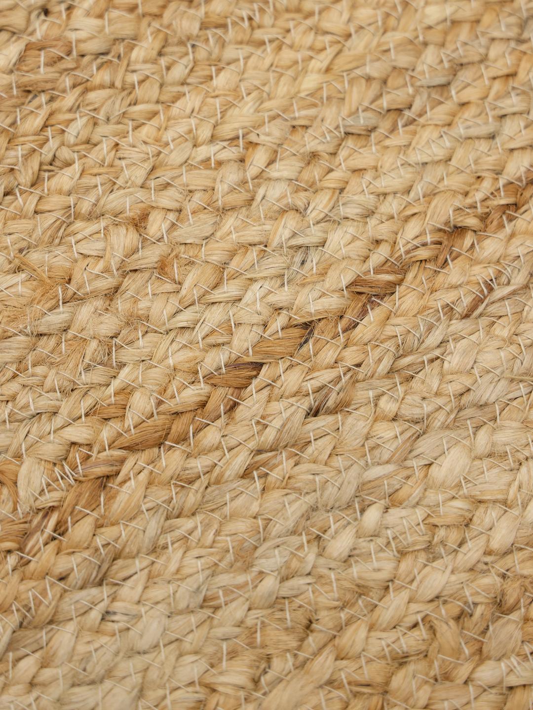 Beige tæppe med et naturligt flettet kantdesign