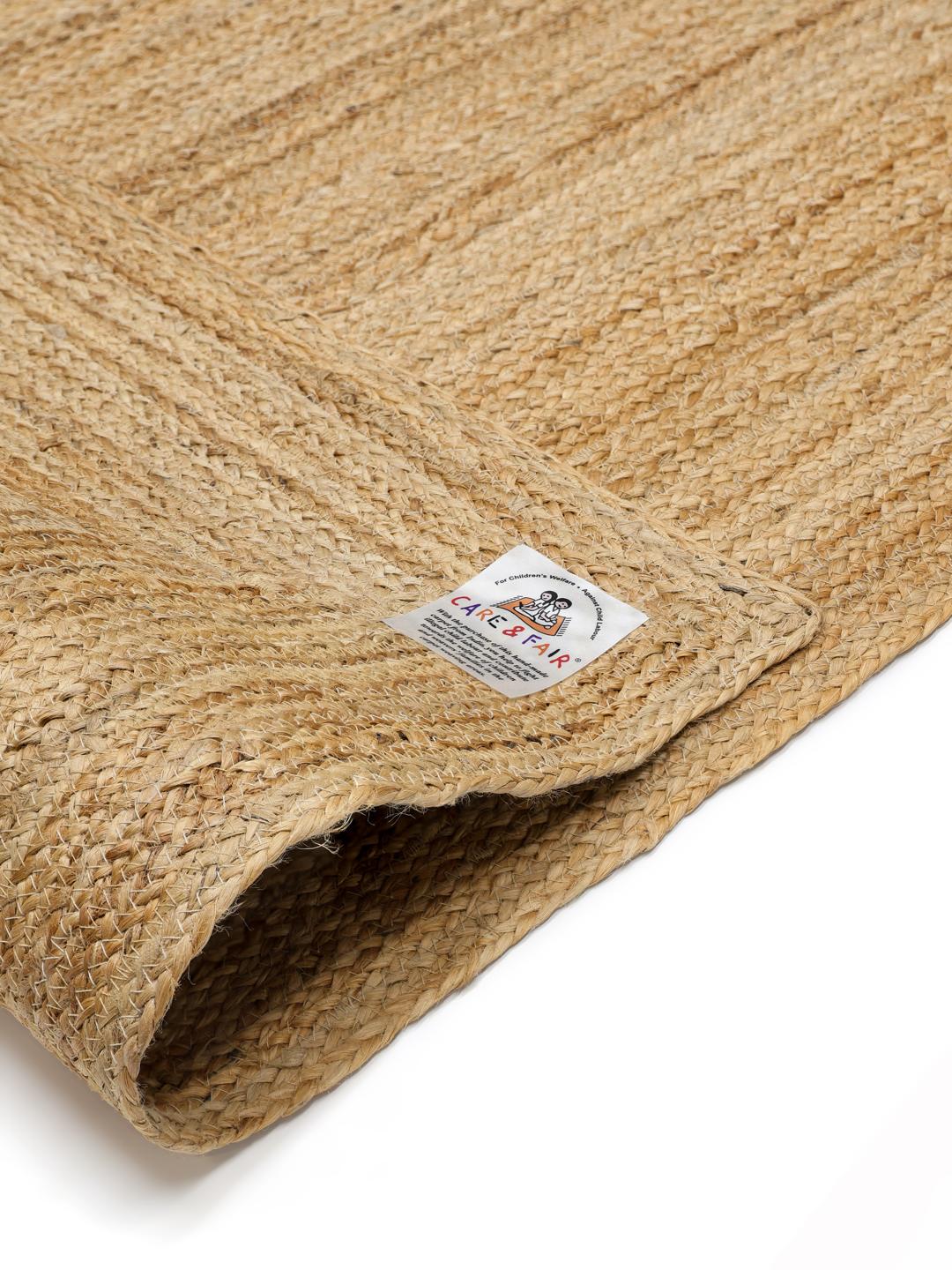 Beige tæppe med et naturligt flettet kantdesign