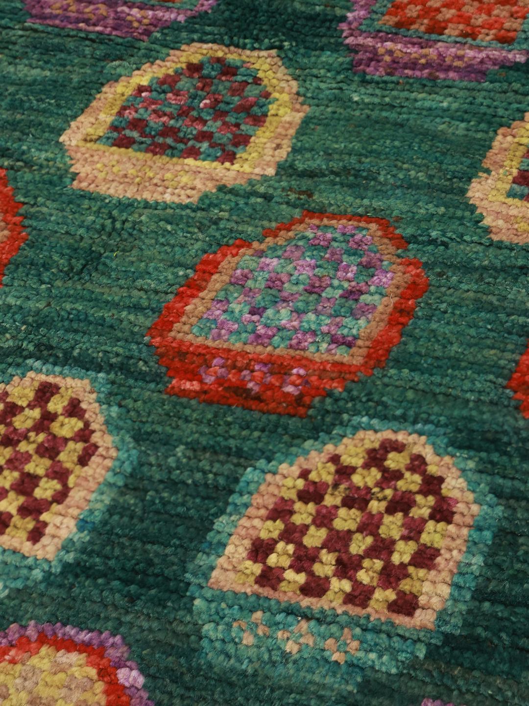 Hand-knotted Afghan rug with a vibrant green field and colourful geometric motifs.