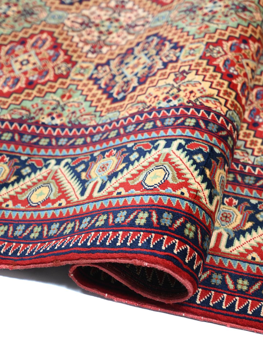 Handmade runner rug from Afghanistan in red with traditional patterns.