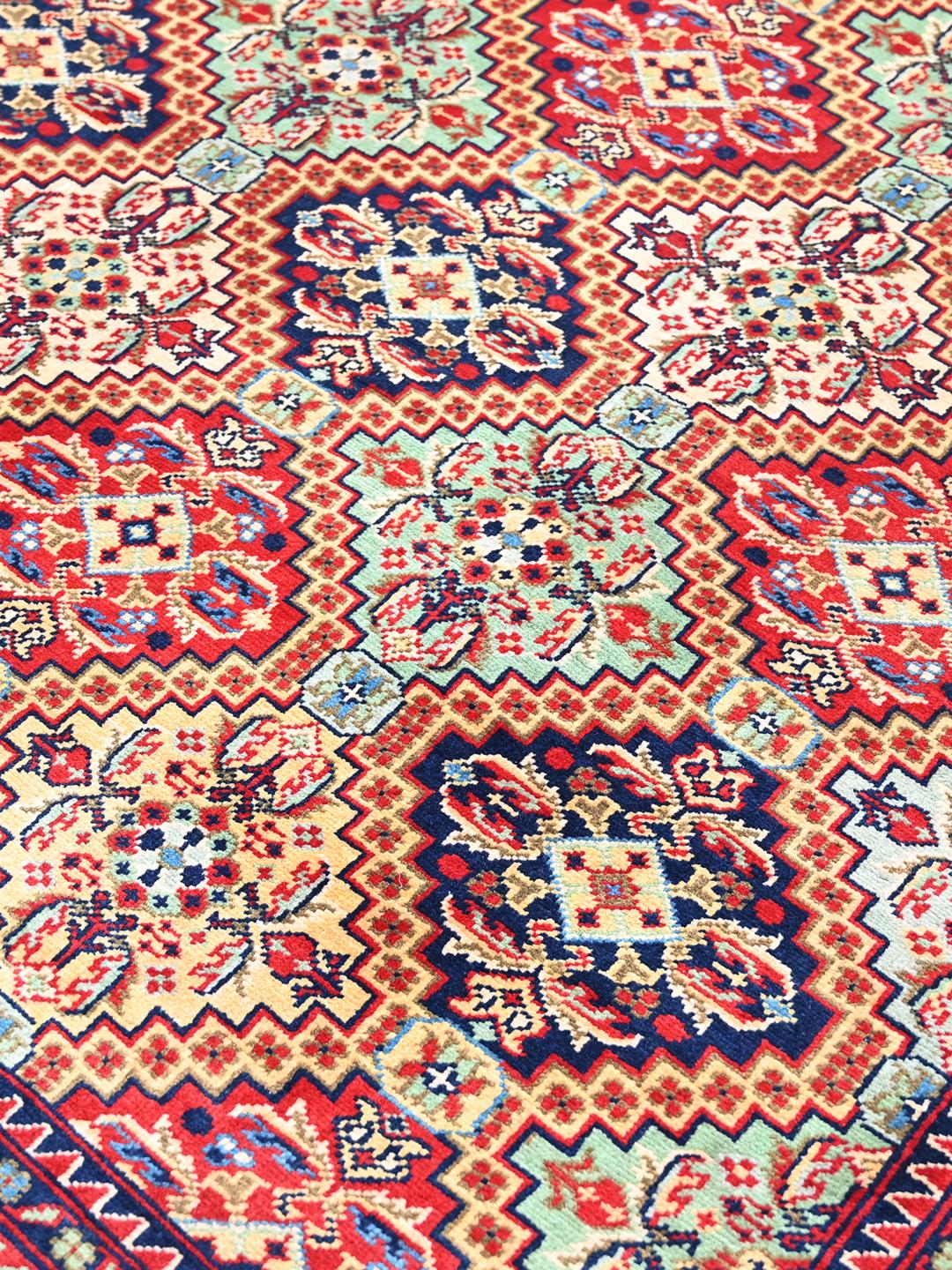 Handmade runner rug from Afghanistan in red with traditional patterns.