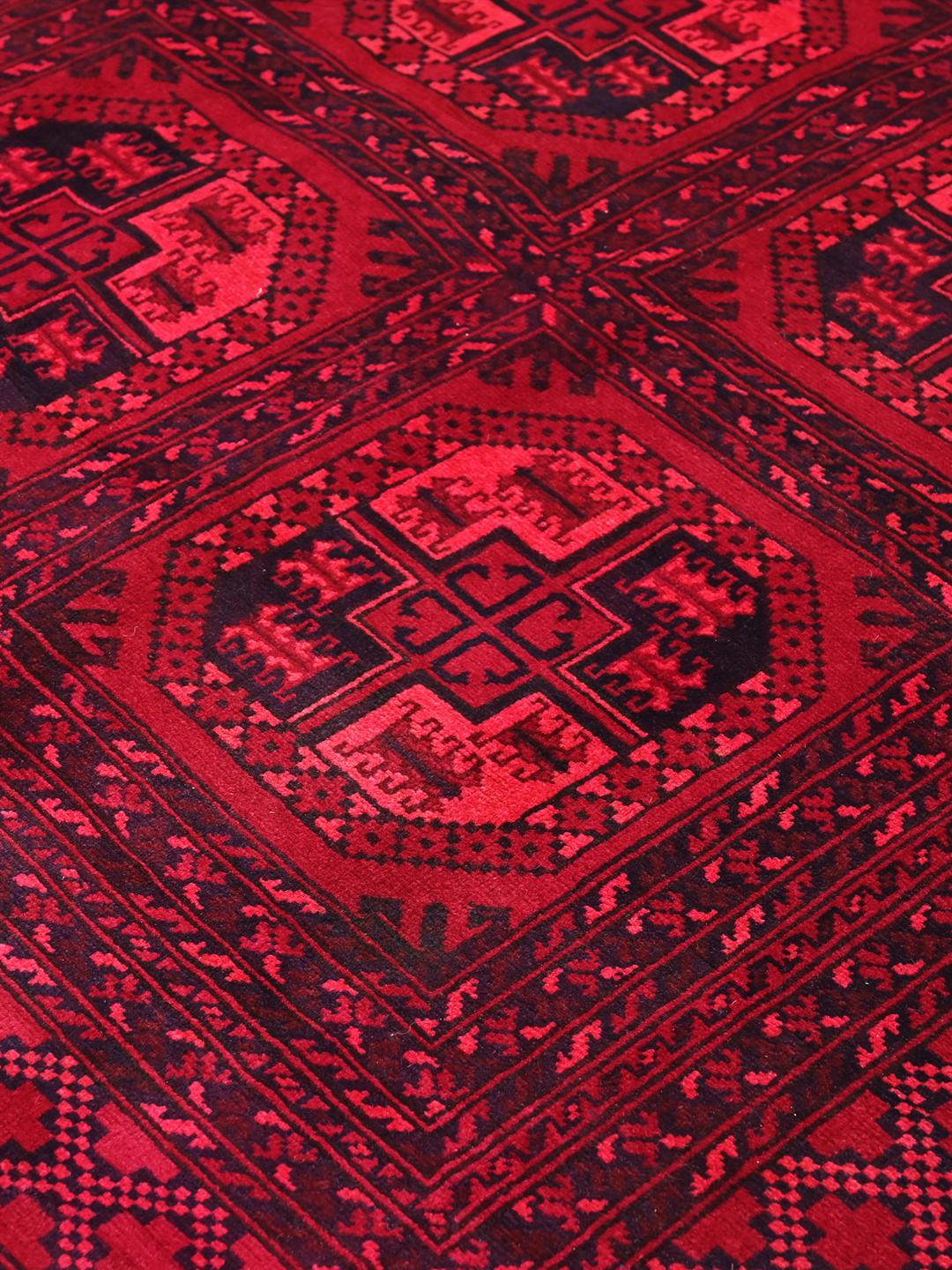 Tapis afghan Kunduz rouge noué à la main avec des motifs géométriques en médaillon.