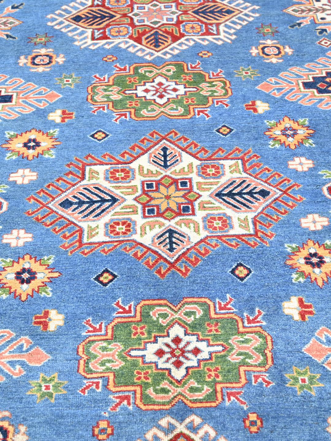 Una alfombra Kazak azul anudada a mano con medallones geométricos e intrincados bordes de Afganistán.