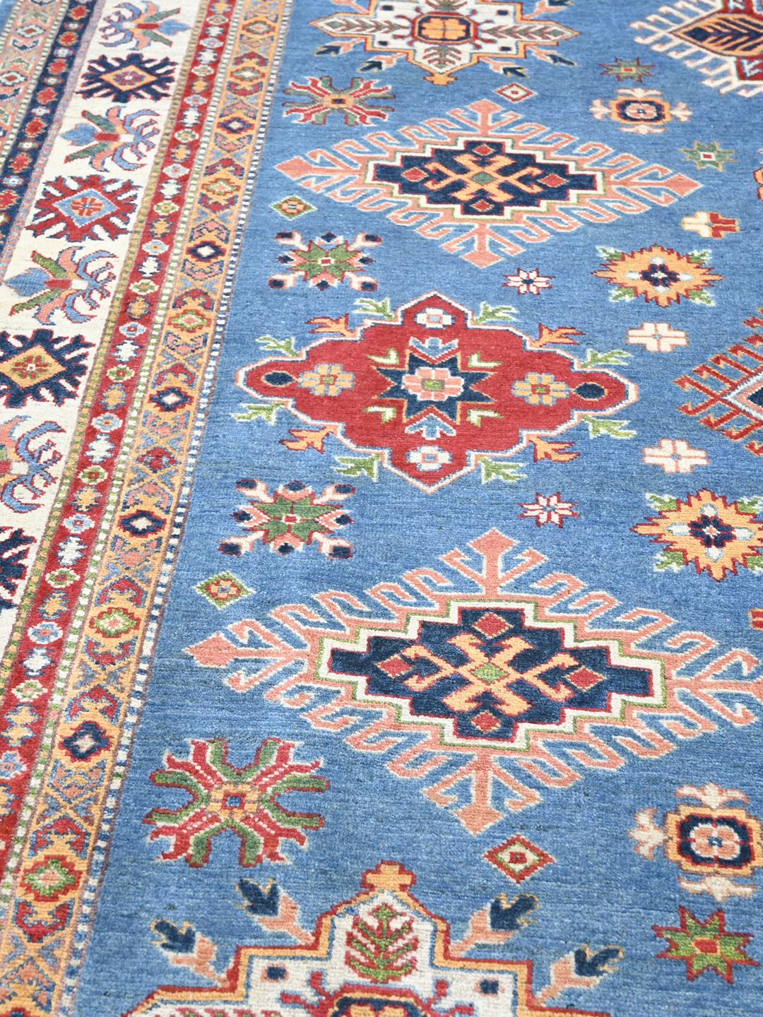 Una alfombra Kazak azul anudada a mano con medallones geométricos e intrincados bordes de Afganistán.