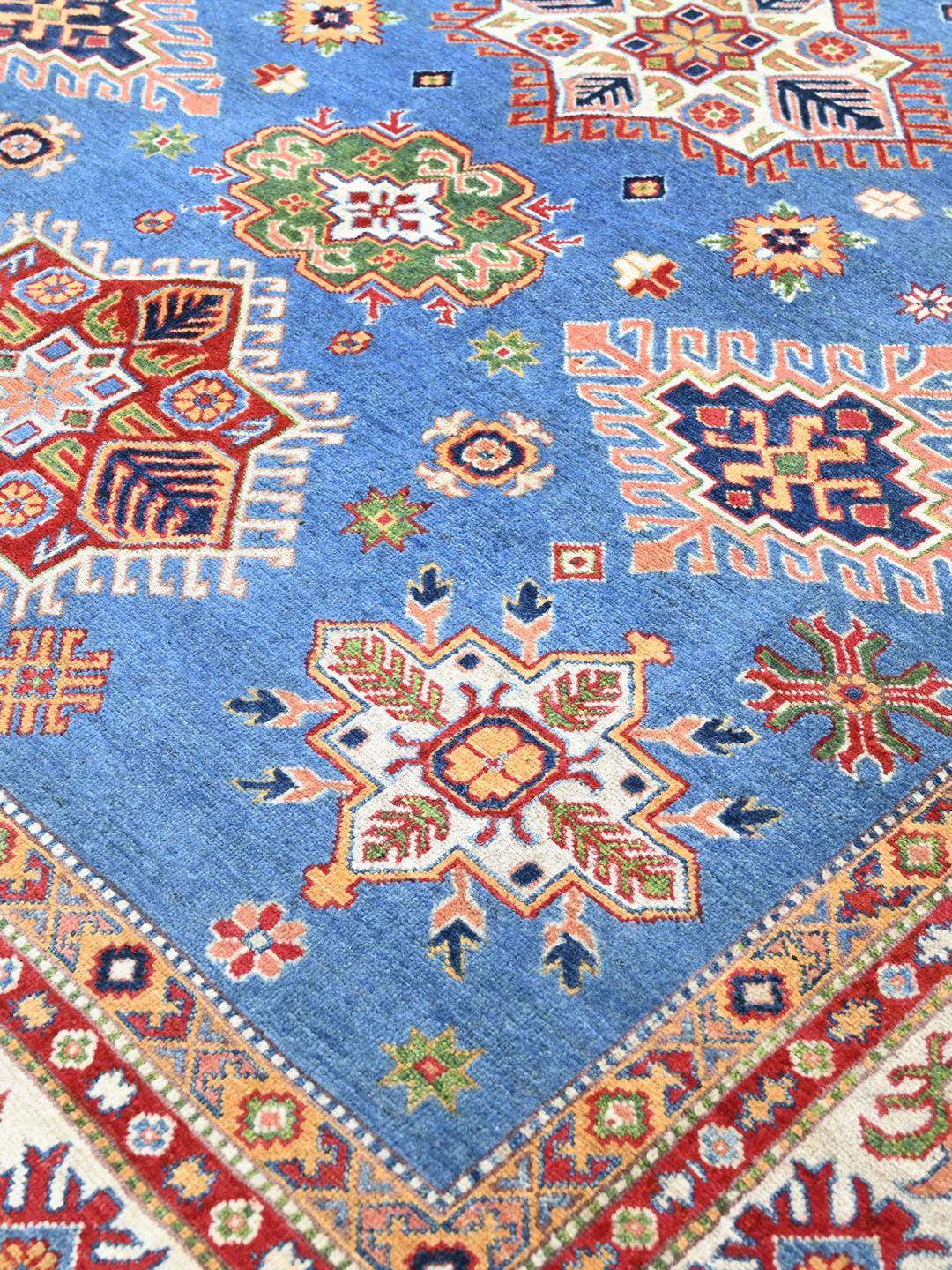 Una alfombra Kazak azul anudada a mano con medallones geométricos e intrincados bordes de Afganistán.