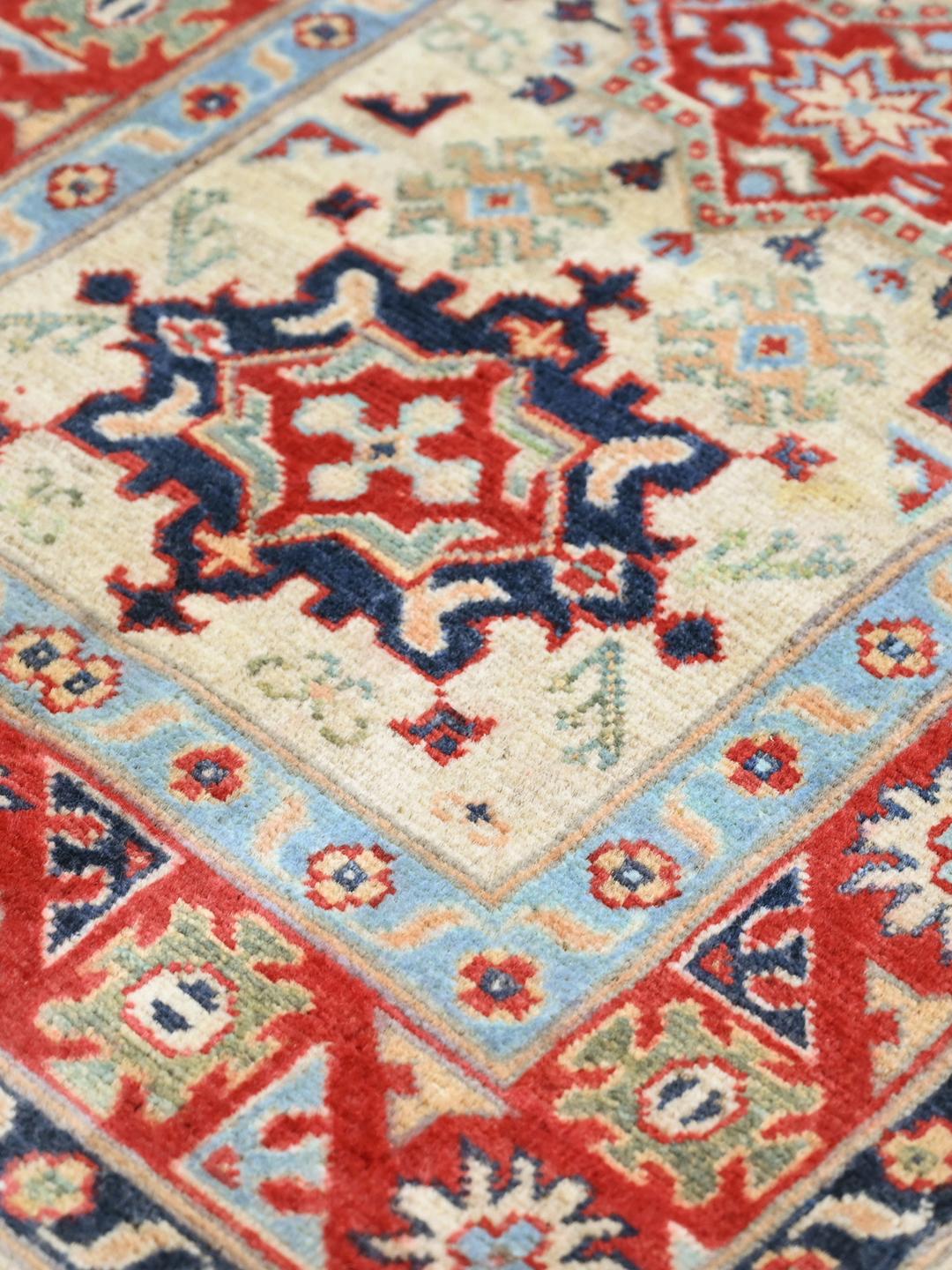 Hand-knotted Afghan Kazak Fine rug in red and blue featuring traditional tribal medallions
