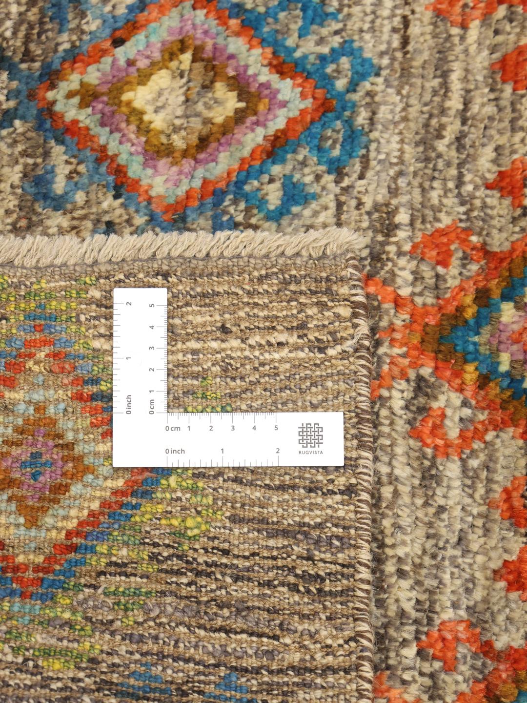 Hand-knotted Afghan rug with colourful geometric patterns on a grey background