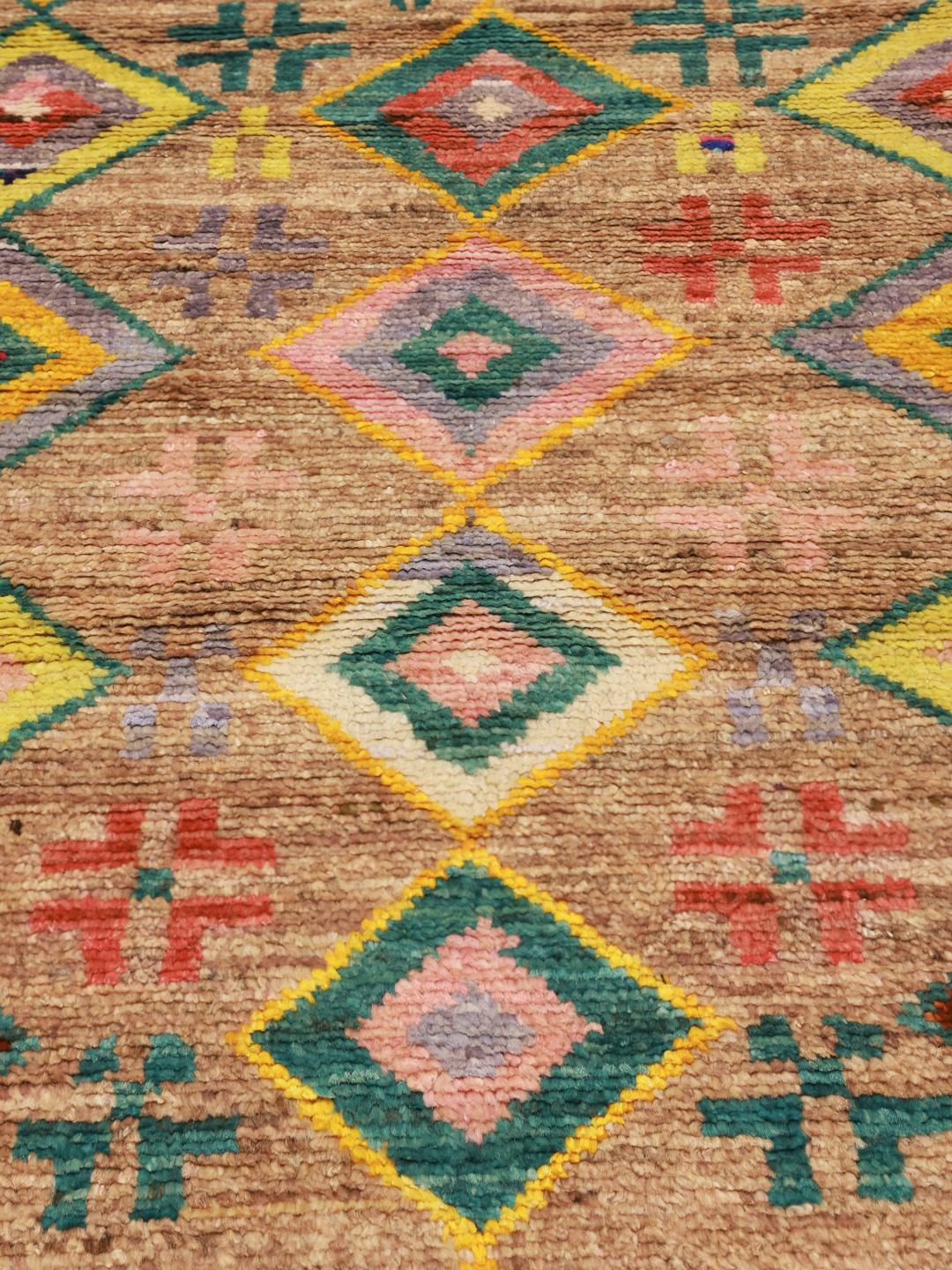 Håndknyttet afghansk tæppe med levende geometriske diamantmønstre i en beige farvepalette.