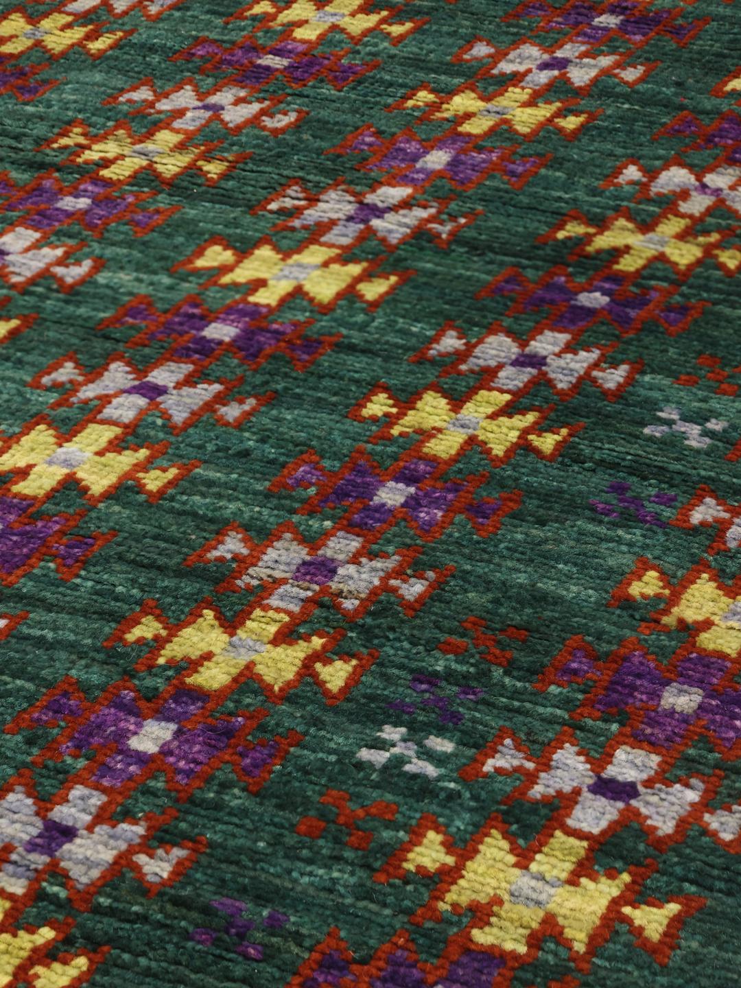 Håndknyttet afghansk tæppe med et dybgrønt felt og farverige geometriske motiver