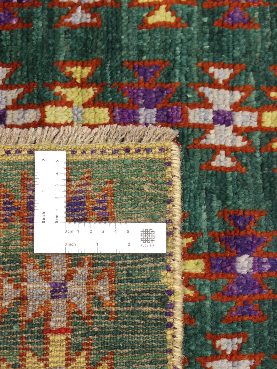 Håndknyttet afghansk tæppe med et dybgrønt felt og farverige geometriske motiver