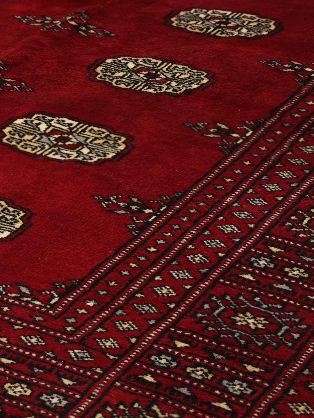 Hand-knotted Pakistani wool rug in dark-red with traditional geometric patterns