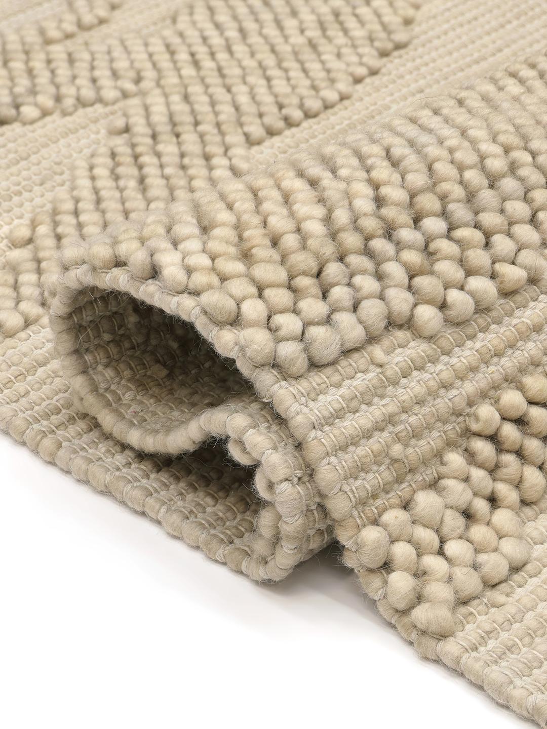Handgeweven beige vloerkleed met een gestructureerd organisch patroon