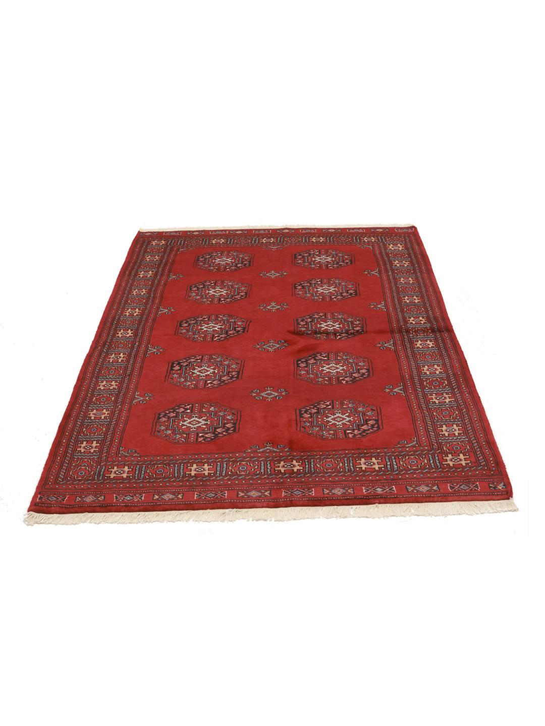 Red rug from Pakistan with traditional geometric motifs.