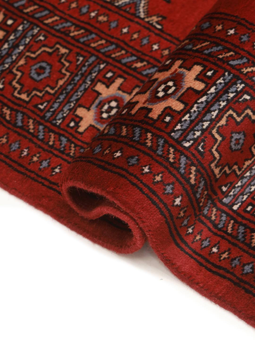 Red rug from Pakistan with traditional geometric motifs.