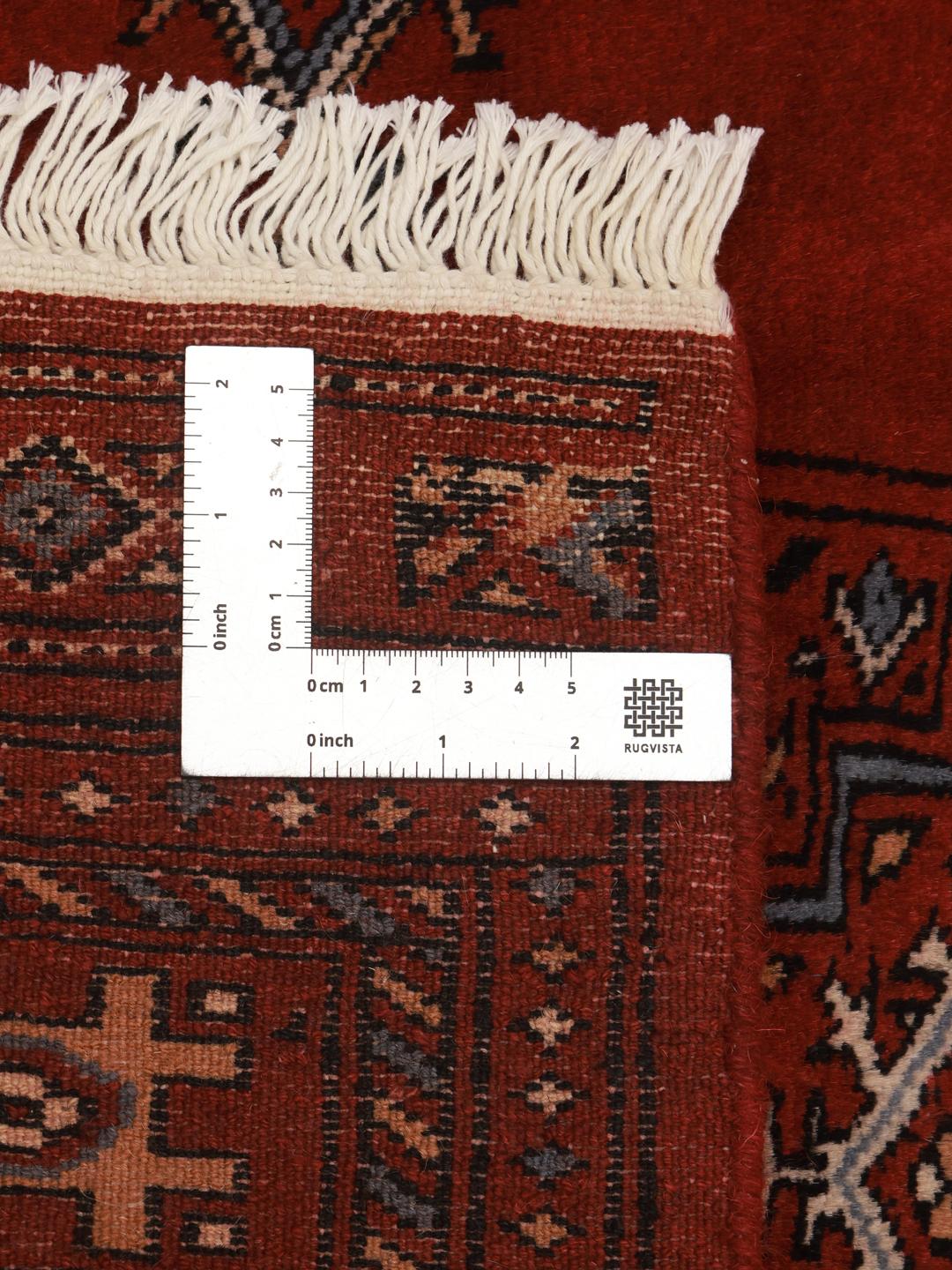 Red rug from Pakistan with traditional geometric motifs.