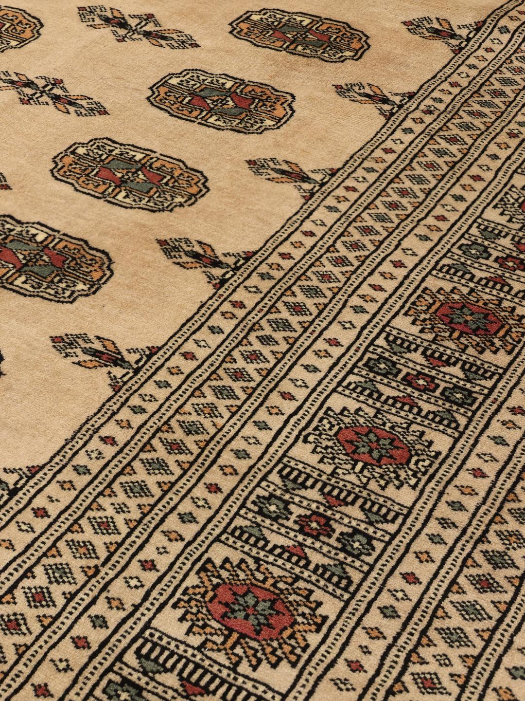 Håndknyttet beige Pakistan Bokhara-tæppe med traditionelle gul-motiver.