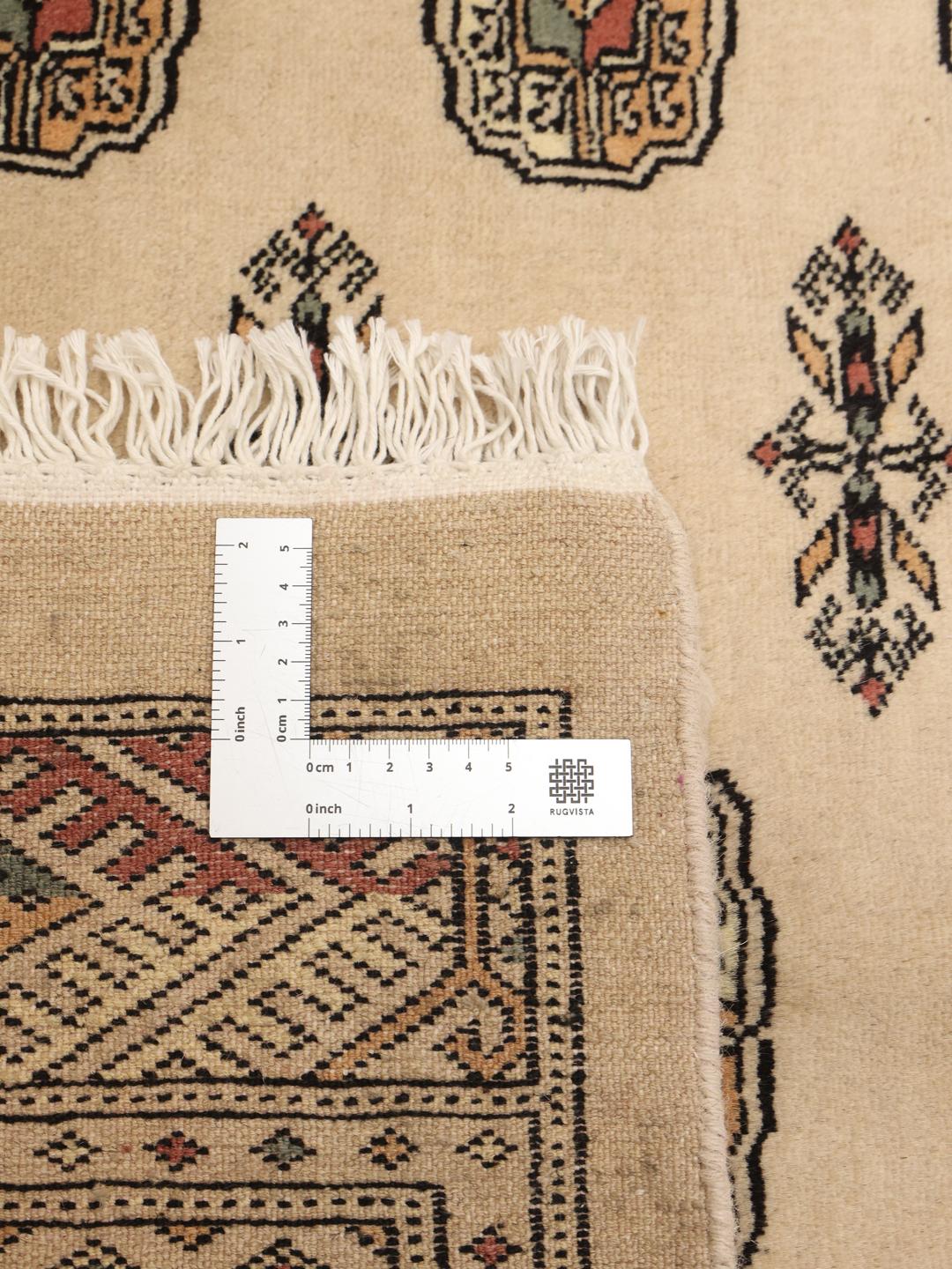 Håndknyttet beige Pakistan Bokhara-tæppe med traditionelle gul-motiver.
