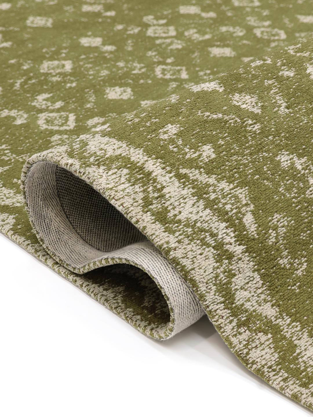 Handgeweven groen vloerkleed met een vervaagd geometrisch patroon en decoratieve rand