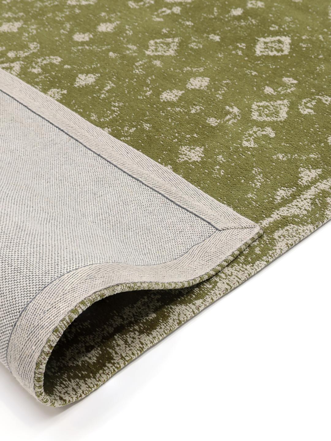 Handgeweven groen vloerkleed met een vervaagd geometrisch patroon en decoratieve rand