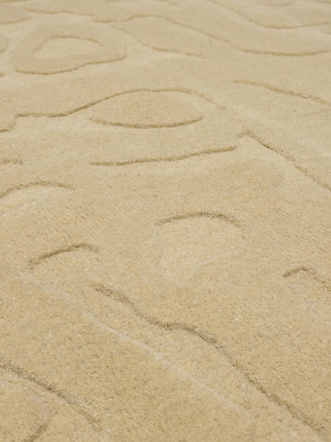 Een modern handgetuft beige vloerkleed met een abstract hoog-laag reliëfpatroon
