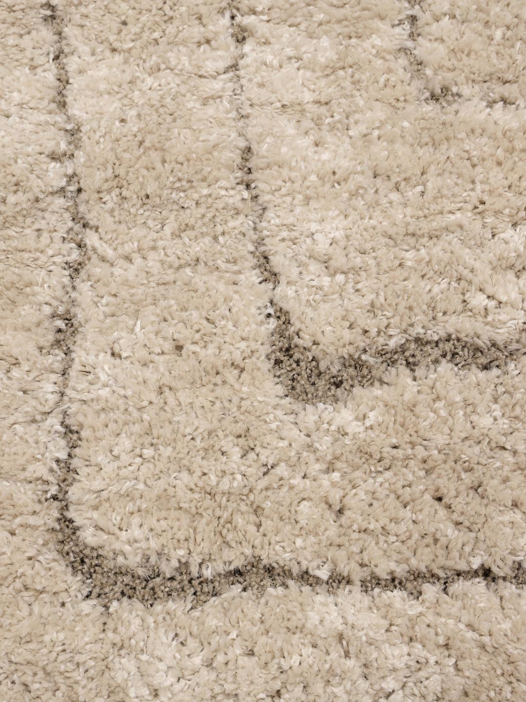 Een hoogpolig beige vloerkleed met organische concentrische rechthoekige lijnen