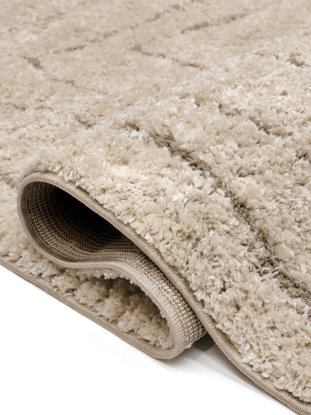 Een hoogpolig beige vloerkleed met organische concentrische rechthoekige lijnen