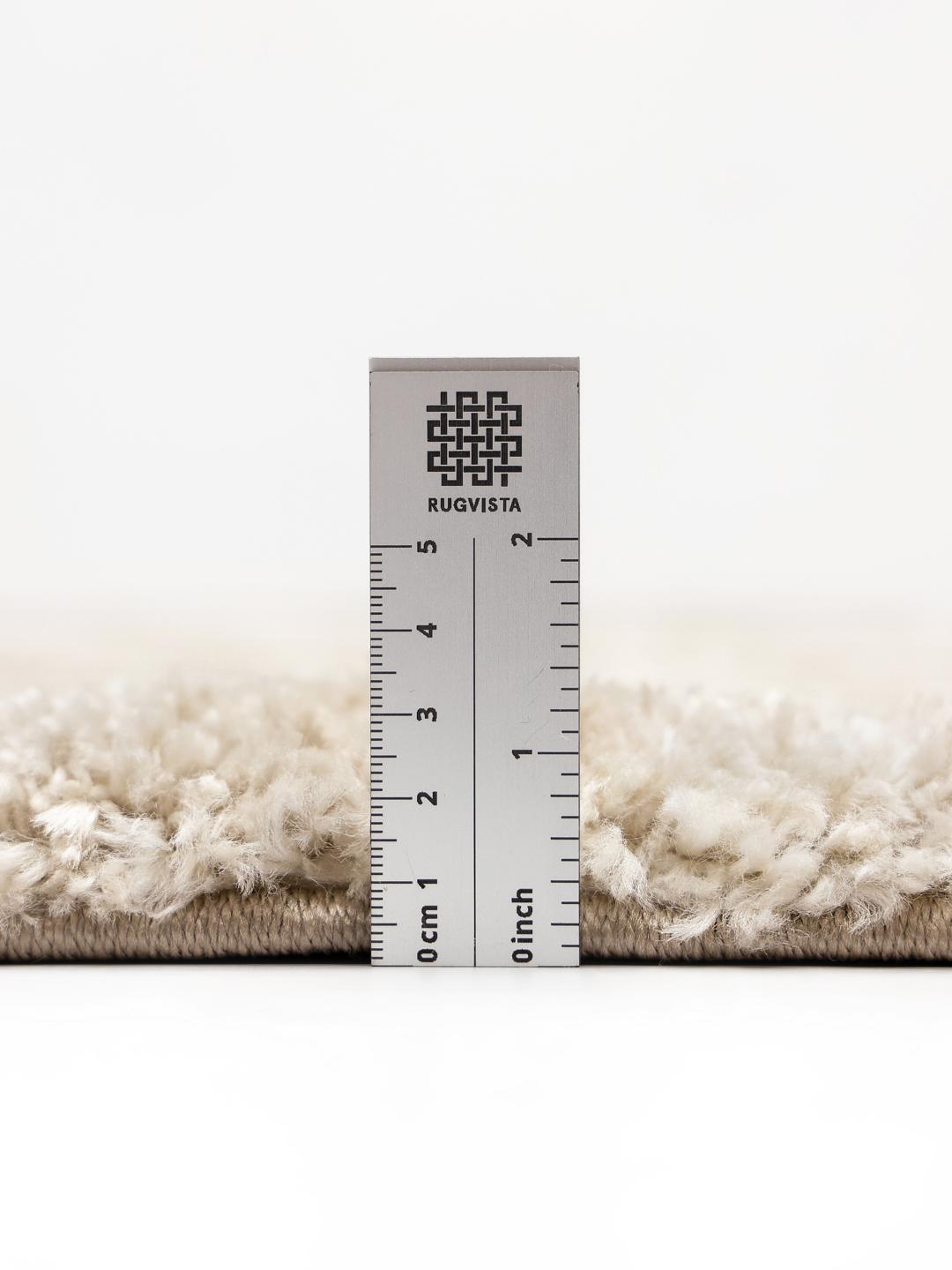 Een hoogpolig beige vloerkleed met organische concentrische rechthoekige lijnen