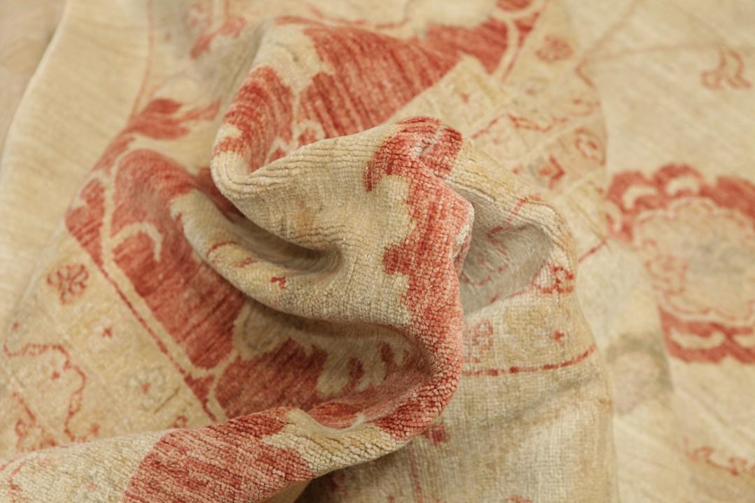 A large hand-knotted rug from Pakistan featuring a beige field and terracotta floral border.