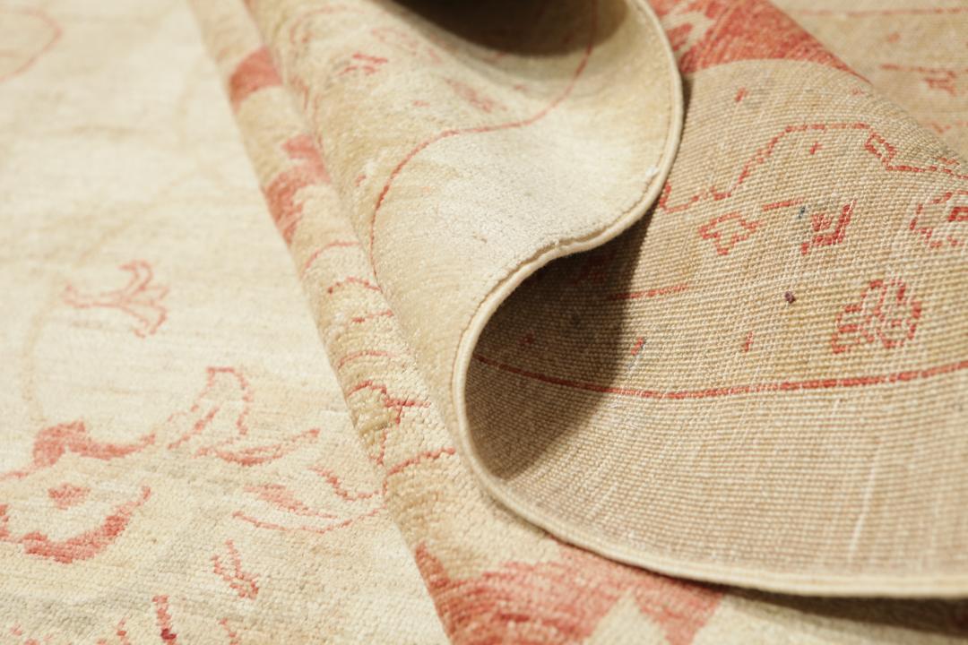 A large hand-knotted rug from Pakistan featuring a beige field and terracotta floral border.