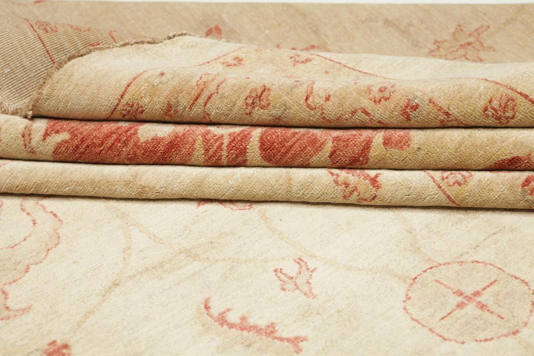 A large hand-knotted rug from Pakistan featuring a beige field and terracotta floral border.